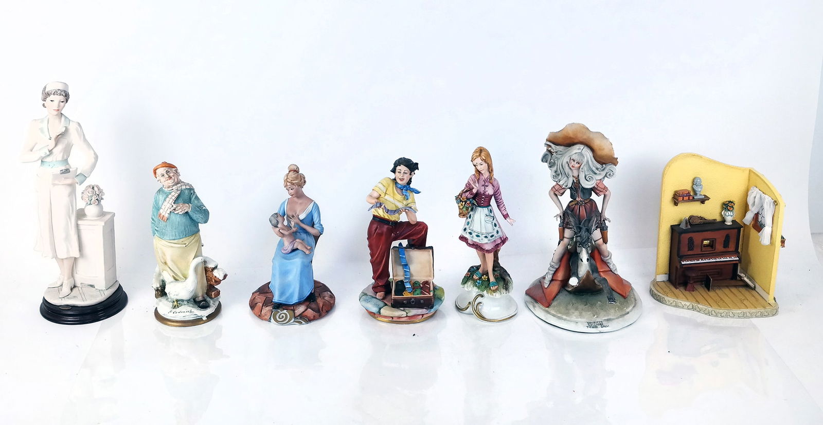 Seven Modern Italian Porcelain Groups: Seven (7) modern Italian porcelain groups, comprising women, men, a fantasy woman on a donkey and a piano scene. [Tallest: 14" H].