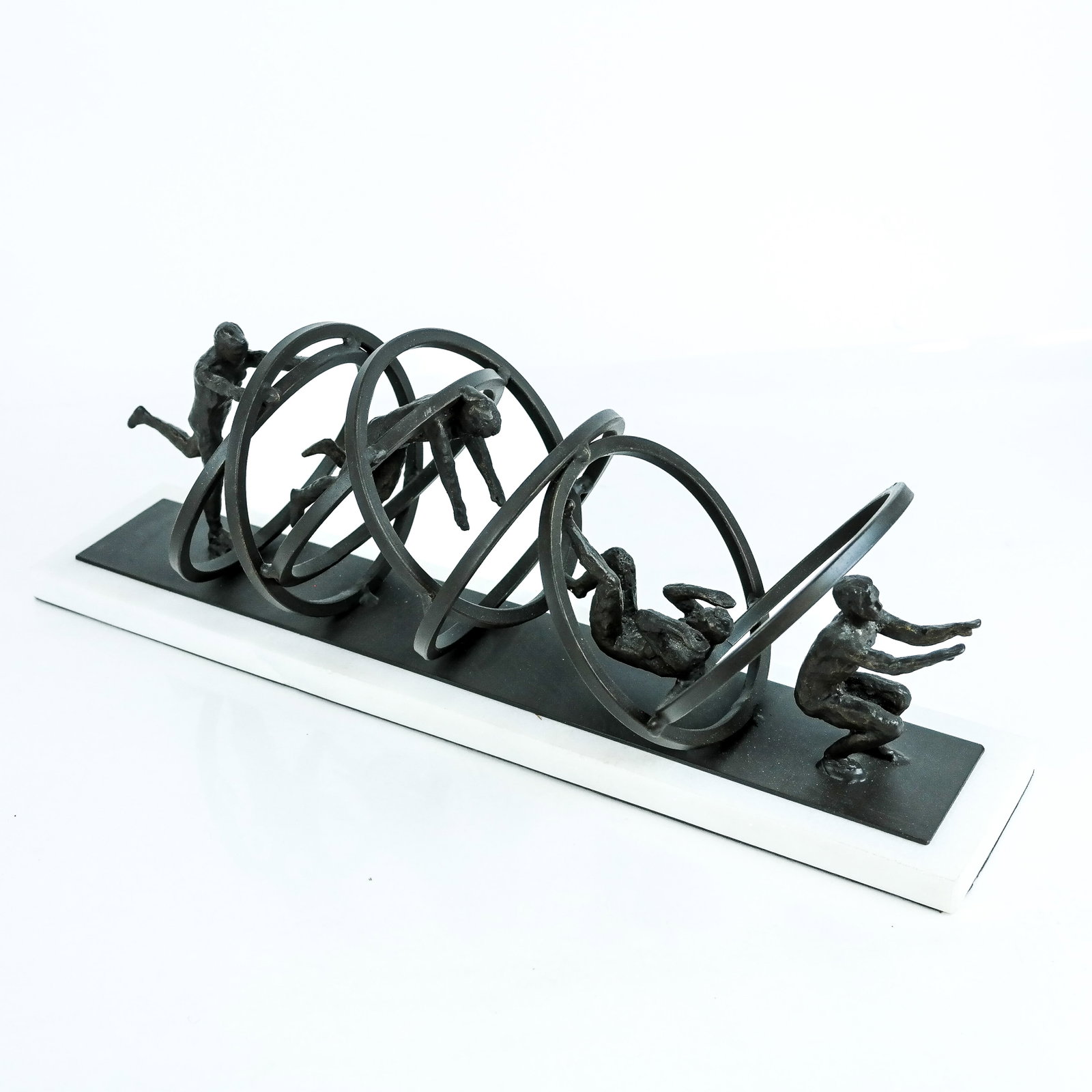 Patinated Iron Sculpture by Global Visions: Patinated iron on marble base sculpture by Global Visions, titled "Jumping Through Hoops", depicting four figures in acrobatic poses and large hoops. [6 1/2" H x 19" W x 6" D].