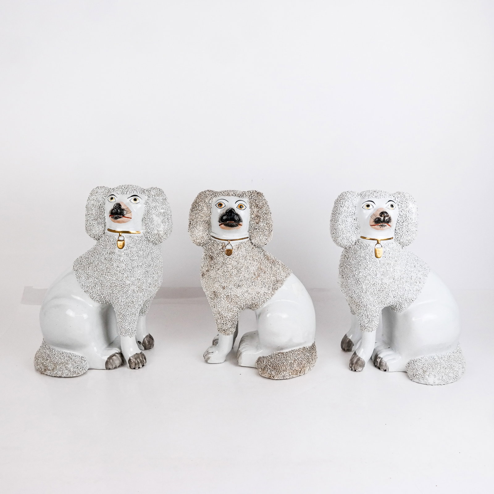 Three Staffordshire Spaniels: Three (3) Staffordshire King Charles spaniels, comprising a pair of white with textured fur, bearing sticker "Leticia Lundeen Ceramics, circa 1865", together with a single spaniel in off-white with te