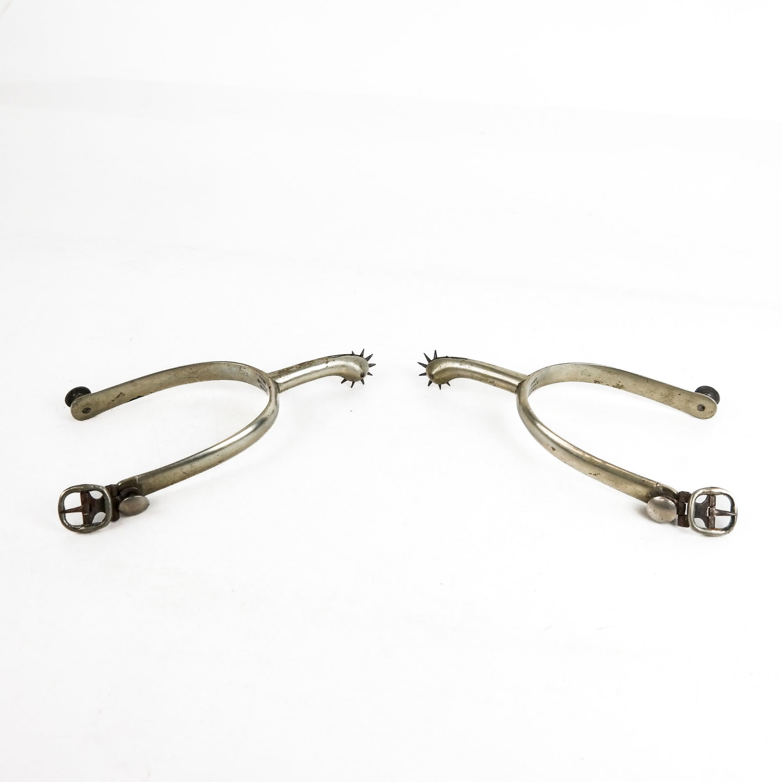 Pair of German Stirrups: Pair of German stirrups labeled "Best German Silver", with buckles and pointed wheel spurs. 7 ozt. [6" x 4"].