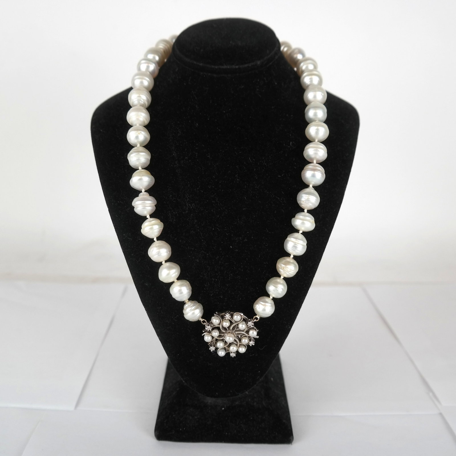 22" Strand Pearl, Diamond and 14K Gold Necklace: 22" strand of large baroque pearls, having a 14K white gold, diamond, and pearl clasp. 20th century, American. In good condition.