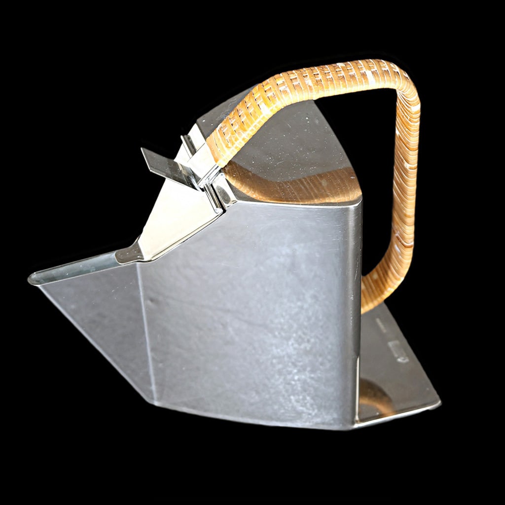 Modern Chrome Teapot: Modern chrome teapot by Alessi, Italy, having angular modern design with raffia wrapped handle. Provenance: From the Collection of renowned architect and designer Thierry Despont. [8" H x 5" W x 9" D]