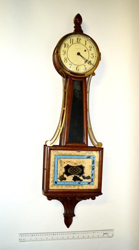 Waltham Banjo Clock: Wood and brass banjo clock with open work brass trim. As is, églomisé lower door. Acorn form finial with pendulum. 40 1/4" H.