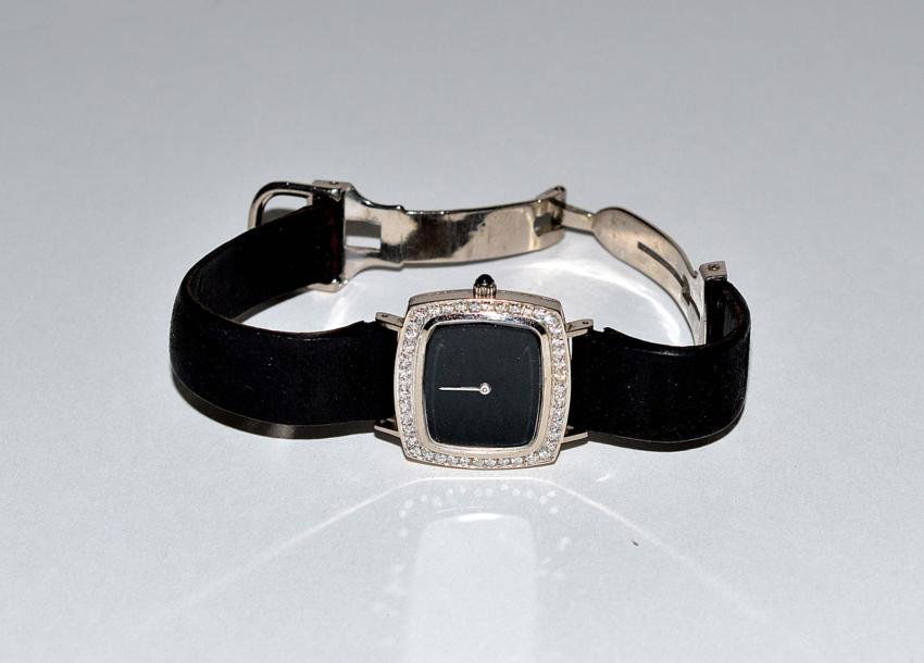 18k White Gold Piaget Watch: Having 44 .01 carat round diamond bezel and deployant buckle; Movado quartz movement, leather strap.