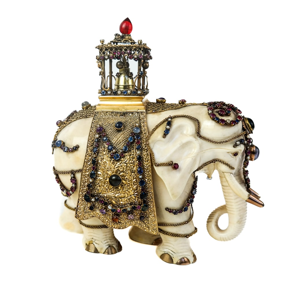An Elaborate Bejeweled Bone Elephant: A bejeweled bone elephant with precious stones and elaborate gilt decorations with gold tips on tusks. Mountings probably silver vermeil. [7" H x 7" W]. Provenance: From the Estate of Baroness Gabriel