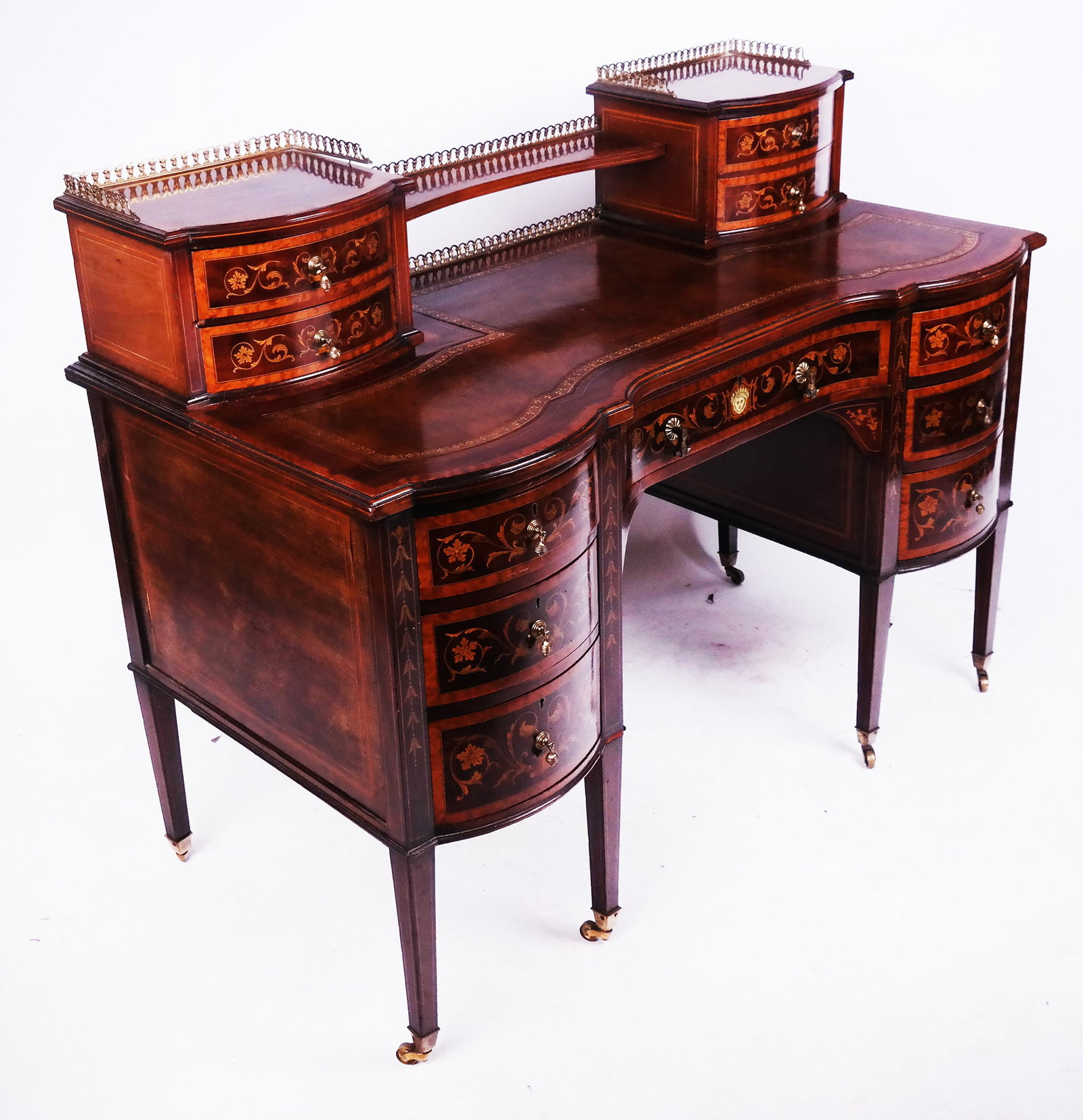 Carlton House Dutch-Style Writing Desk: A Carlton House Dutch-style writing desk, having eleven drawers with scrolling tendril marquetry throughout, stringing and banded inlay, and a tooled leather writing surface with gilt stamped border. 