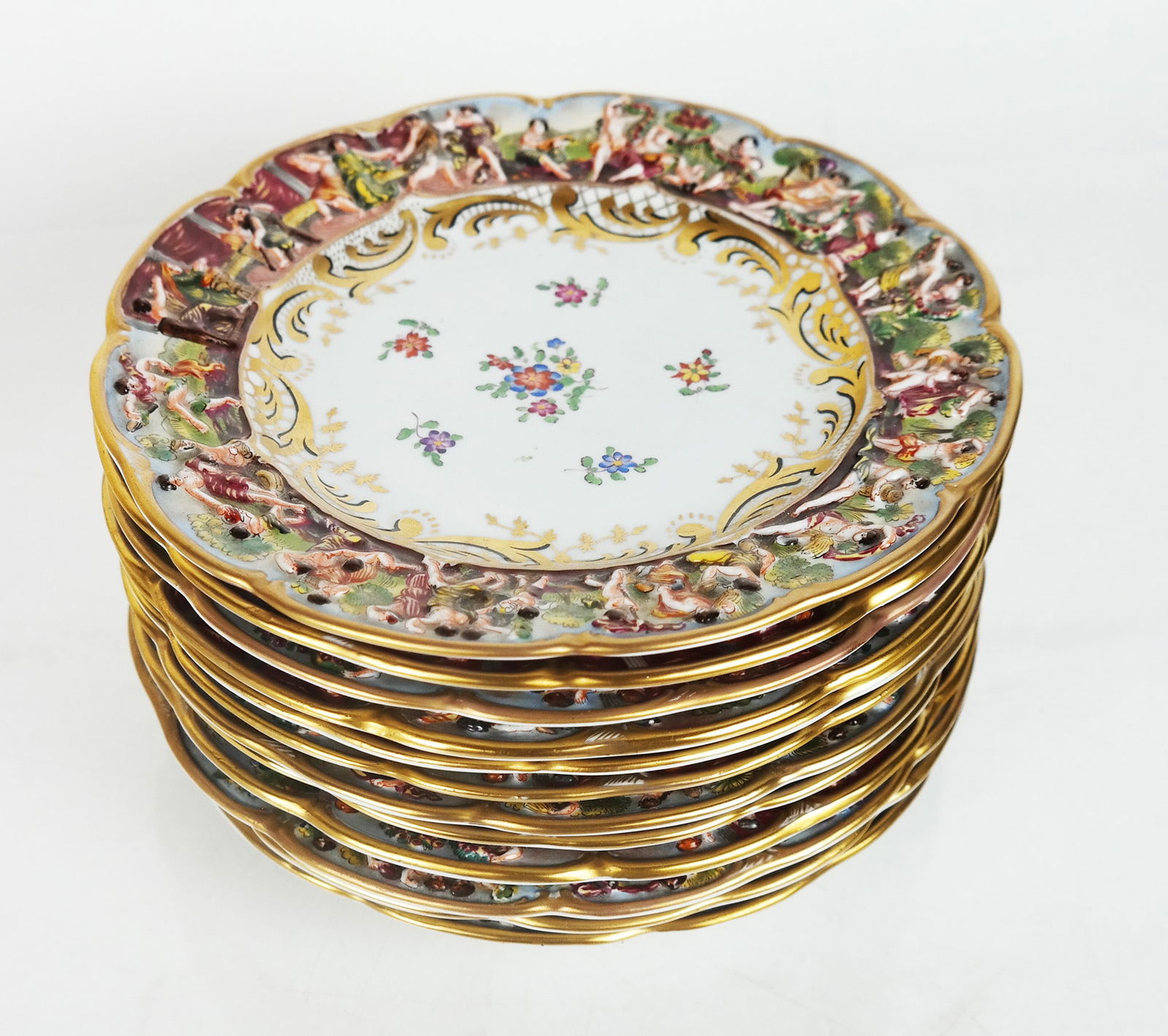 Set of 12 Capodimonte Lunch Plates: Set of twelve (12) Capodimonte luncheon plates having classic putti adorned borders with painted and gilt designs. [9" Diam.].