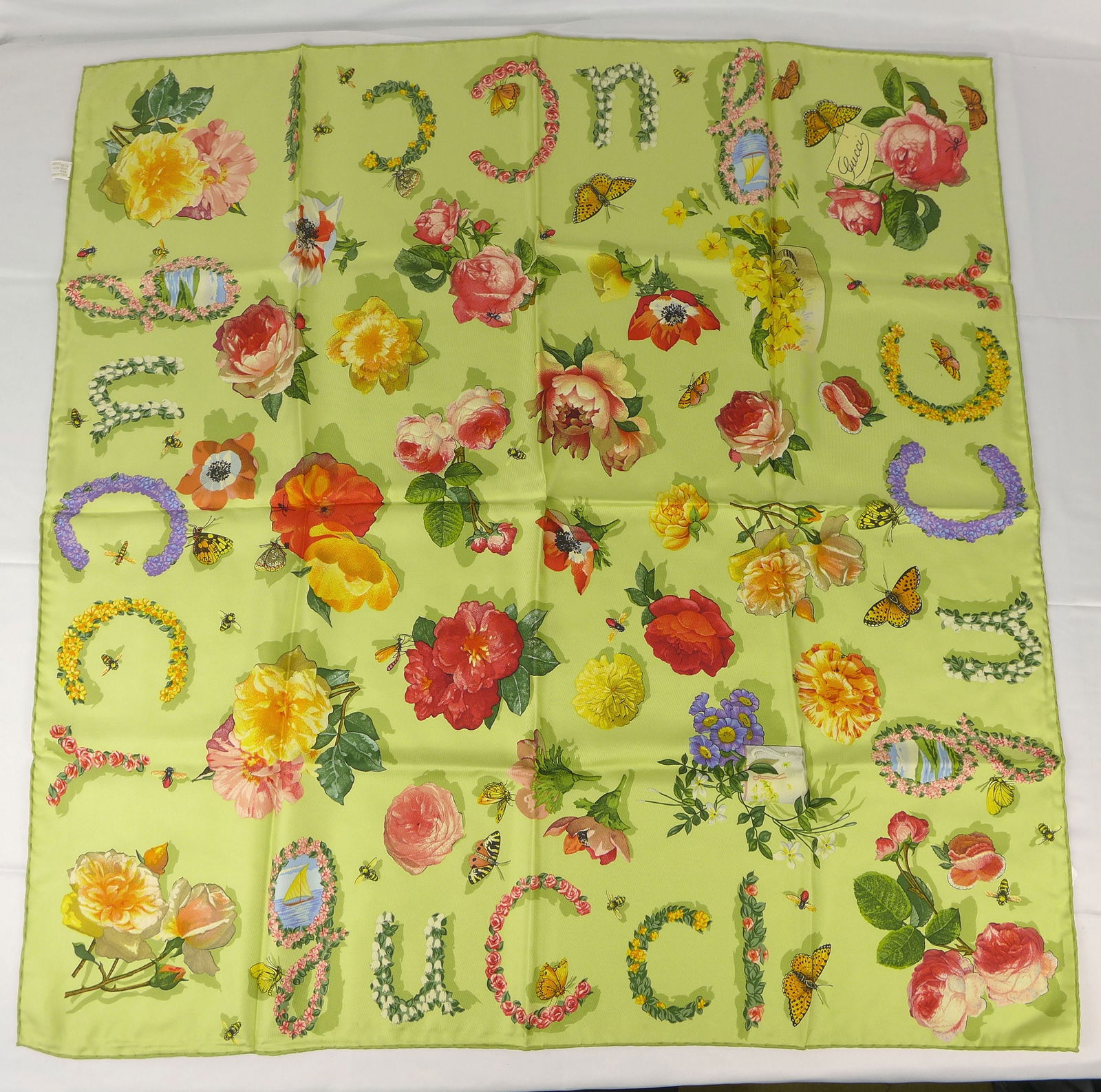 Vintage Gucci Italy Silk scarf New with tags and box "Flowers Insects": This is a Gucci Silk Scarf made in Italy dating from the 1990's early 2000's. Decorated with multiple flowers and insects bordered with the Word gucci spelled out in flower design. In new condition wi