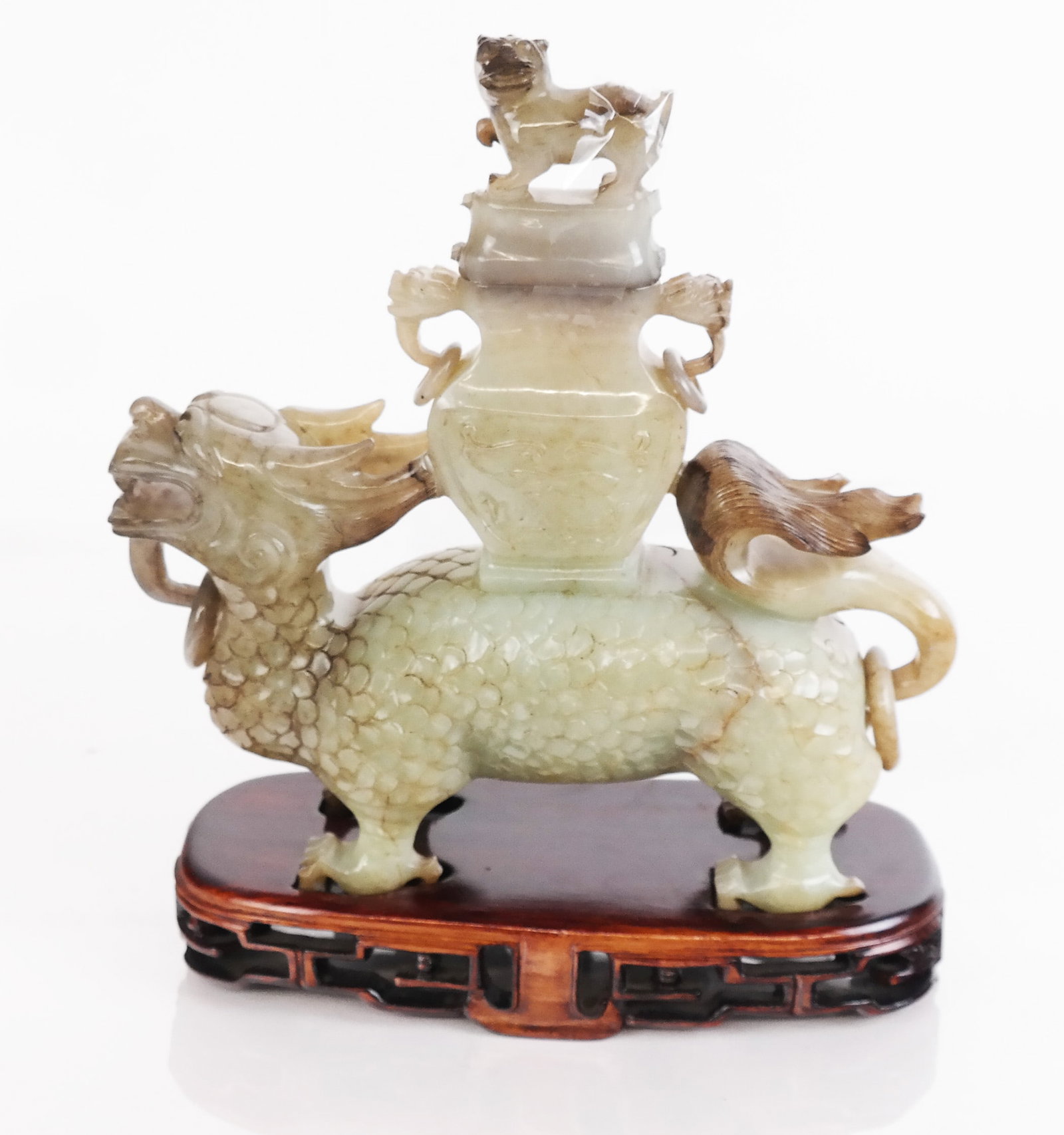 Chinese Carved Jade Temple Lion Censer: Chinese carved jade temple lion censer, the lion with scaled body, wavy tail and horns, carrying a lidded censer, now on a carved base. [8 1/4" H x 7 1/2" W x 3 1/4" D]. Residue; losses to censer lid;