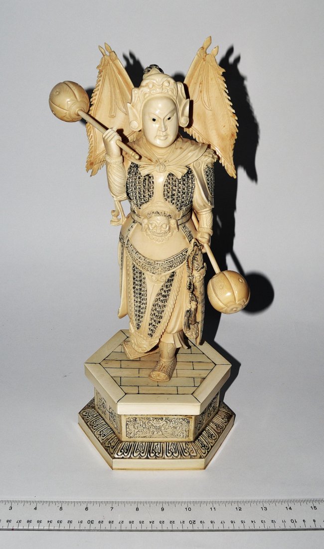 Chinese Carved Ivory Warrior Figure: Full-length standing depiction of a traditional warrior in a chain mail armor with battle standards and mace weapons. 7" W x 5 3/4" D x 16 1/2" H. In good condition.