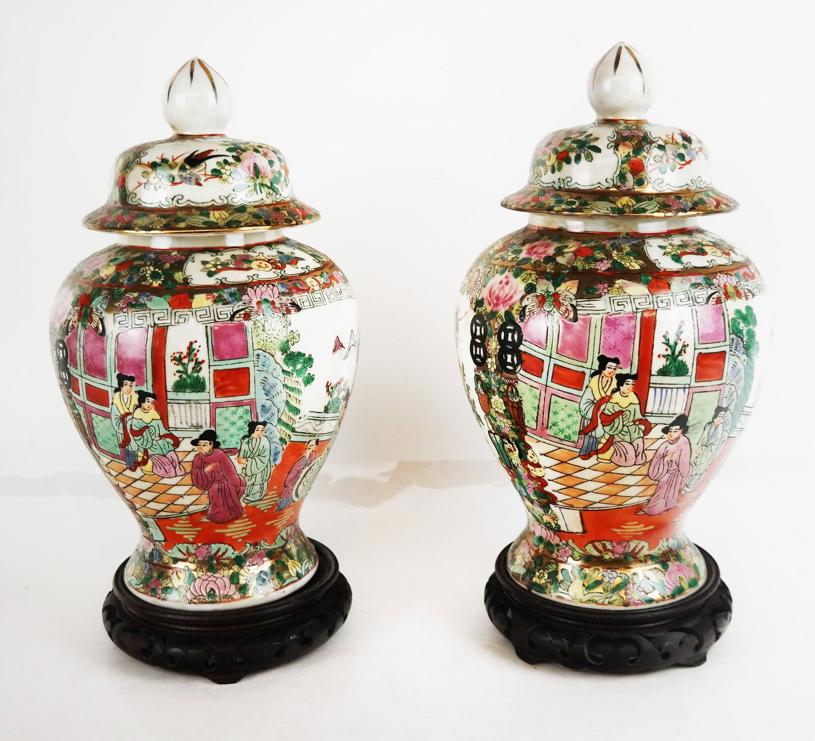 Pair of Chinese Rose Medallion Ginger Jars: Pair of Chinese rose medallion porcelain ginger jars, the covers and vases with floral and scenic decoration, bearing red character marks to bases, with carved wood stands. [12 1/2" H x 7 1/4" Diam.].