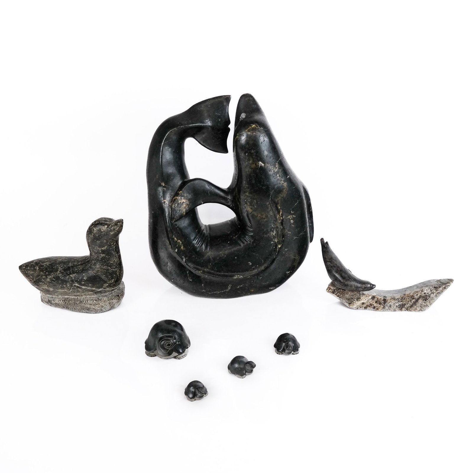 Group of Inuit Carved Stone Animals (7): Group of seven (7) Inuit carved stone animals, probably Pacific-Northwest, comprising a whale, seals and turtles, one marked to base. [Largest: 12 1/4" H x 10" W x 4 1/4" D]. Breaks, losses, marks and