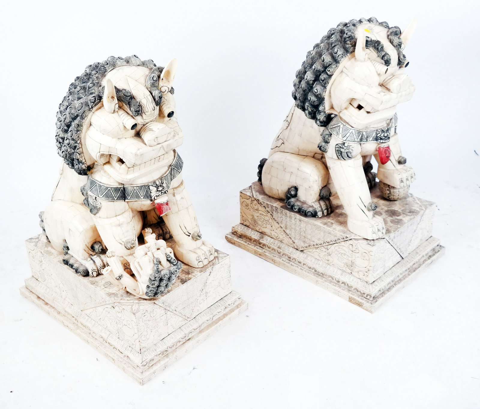 Pair of Chinese Bone Temple Lions: Pair of Chinese scrimshaw palace temple lions, seated on elaborately carved and decorated bases. [30" H x 24" W x 16" D]. Several losses; restoration.