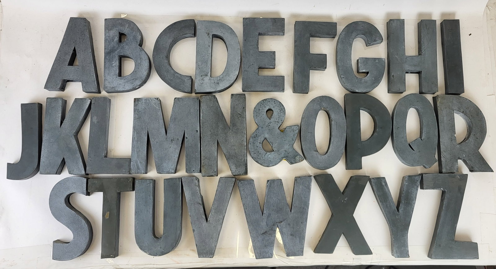 Complete Anthropology Zinc Wall Display Alphabet: Complete zinc wall display alphabet, manufactured for Anthropology, comprising a complete capital letter alphabet plus an ampersand. 27 pieces total. [Each: 8 1/8" H x various widths x 11 1/8" D]. Scu
