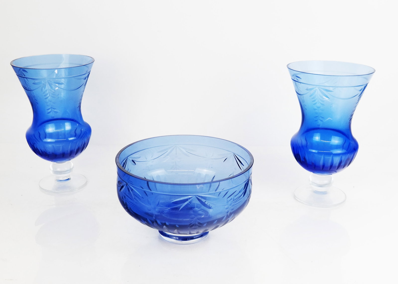 Vintage Blue Glass 3-Piece Garniture: Vintage blue glass garniture, decorated with swags of low-hanging fruit, comprising a pair of urns and a footed compote. [Urns: 9 1/4" H x 6" Diam.]. Condition reports and requests for additional phot