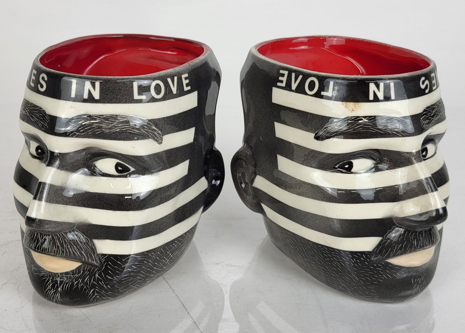 Michael BIELLO: Portrait Mugs, "Clones in Love": Pair of portrait mugs, "Clones in Love". Each signed "Biello" (Michael Biello, American, 20th C.). Provenance: From the Collection of Brendelle & Fred Walden. [4" H x 3 1/2" W x 3" D]. Overall good co