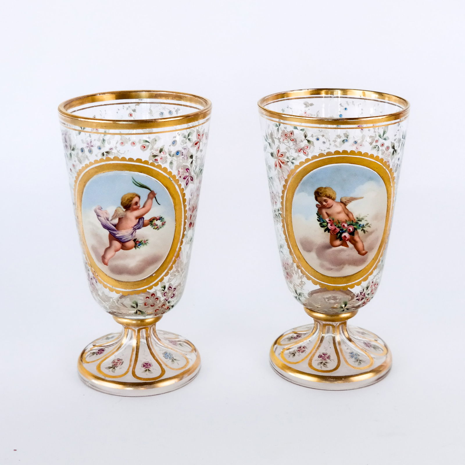 Pair of Viennese Enamel Goblets: A pair Viennese enamel goblets, 19th century, the gilt decorated crystal goblets having faceted bases with porcelain hand painted cupids. [6" H]. Property of an important NY philanthropic family. Cond