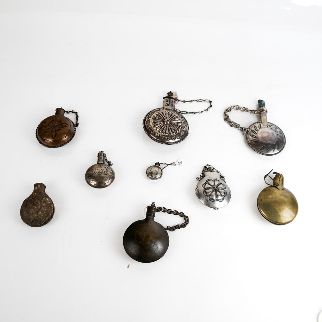 Eight Vintage Metal Flasks: A collection of eight flasks, including some with elaborate designs, one with a turquoise stopper, one with horse design, one with rosette design, and one ceramic. Provenance: From the Collection of B