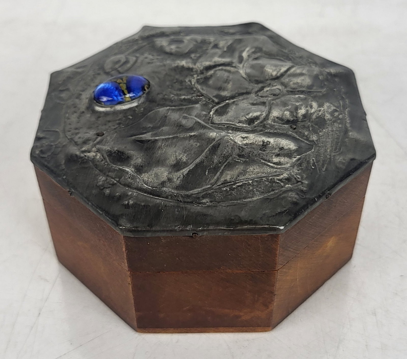 Arts Nouveau Octagonal Box: Arts and Crafts hammered metal-topped wooden box with hinges, having inset glass on lid. [2 3/4" H x 3 3/4" Diam.]. In good condition, with no losses. Condition reports and requests for additional pho
