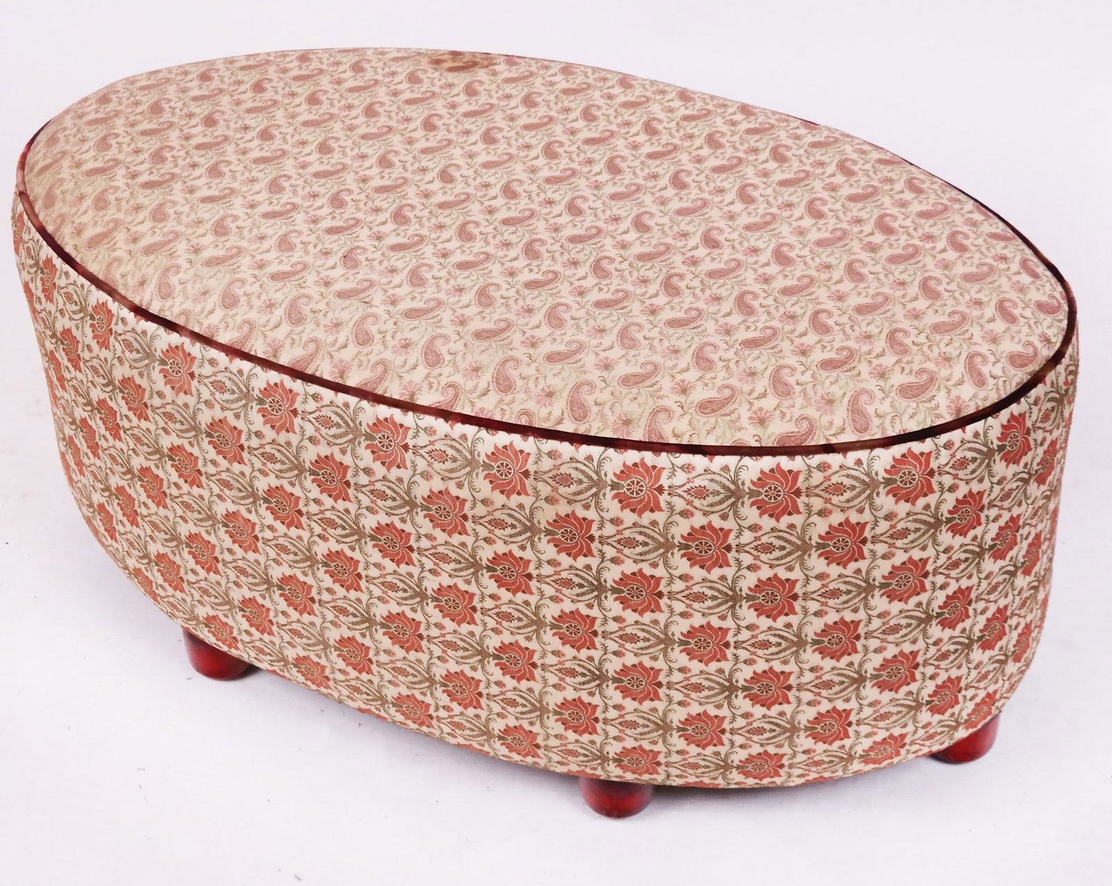 Modern Oval Decorated Ottoman: Large modern oval ottoman - pouffe, of oval outline, with paisley upholstery, resting on bun feet. [18" H x 43" W x 26" D]. Some soiling to fabric. Condition reports and requests for additional photos