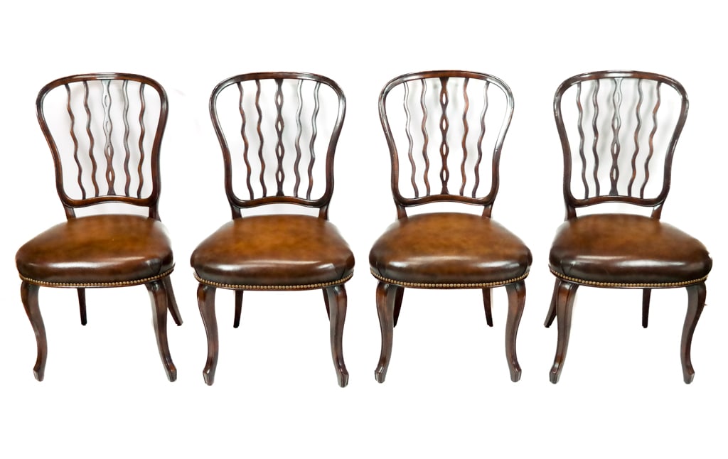 Set of 4 English Mahogany Side Chairs: Set of four chairs with carved mahogany wavy postbacks and studded leather upholstered seats, on carved mahogany legs; retailed by Rinfret of Greenwich, CT. [38" H x 22" W x 25" D]. Property from a We