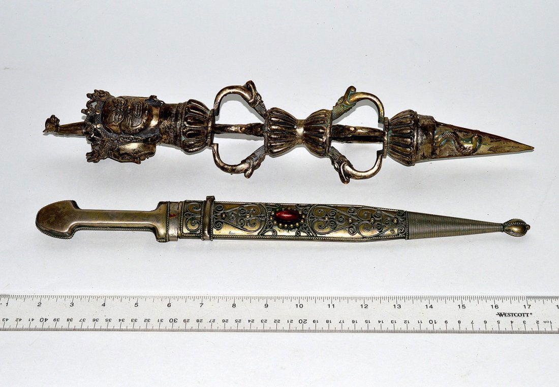Two Ornate Eastern Objects: A filigree decorated dagger with a sheath and a silvered metal obelisk form, having ornate carvings of animals and dieties. Obelisk: 17 1/4"H. Sheath: 16"L.