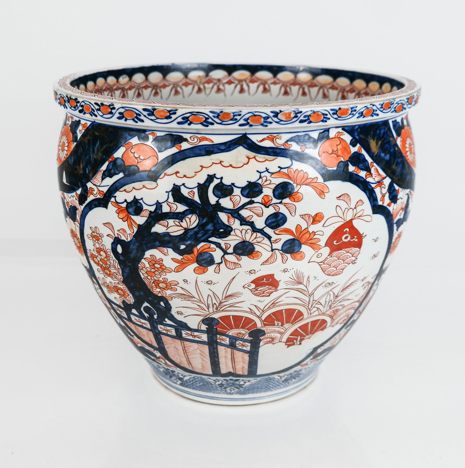Japanese Imari Porcelain Jardiniere: Japanese Imari porcelain jardiniere or fish bowl with landscape and floral design to outer. [11.25" H x 13.25" Diameter]. Overall good condition with a chip to one side and an associated crack.