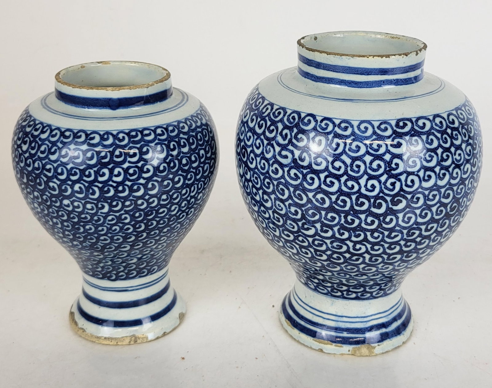 Korean Graduated Pair of Jars: Graduated pair of blue and white decorated ginger jars, with spiral pattern, likely Korean, 19th/20th century. [Taller: 7.25" H x 5.5" Diameter]. Overall good condition with chips to base of each and 