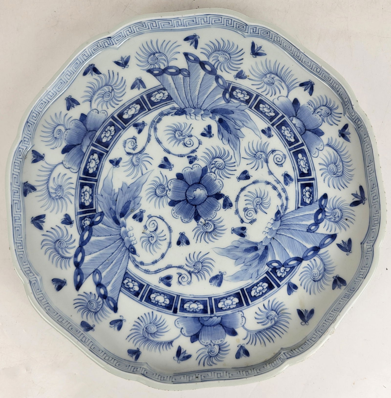 Chinese Qing Dynasty Dehua Decorated Plate: Chinese Qing Dynasty dehua blue and white decorated plate with moths and running spiral around rim; scrollwork decoration to reverse, and with an auspicious inscription at bottom in traditional Chines