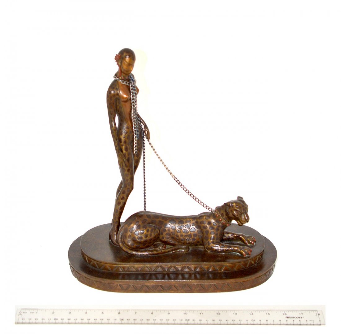 After Erte Bronze "Leopard Woman": Stylized depiction of a standing woman in a leopard spot cat suit with a growling leopard on a chain leash. Signed "Erte" on base. 13 1/2" W x 7" D x 15" H. Bears a rich brownish green patina. In good