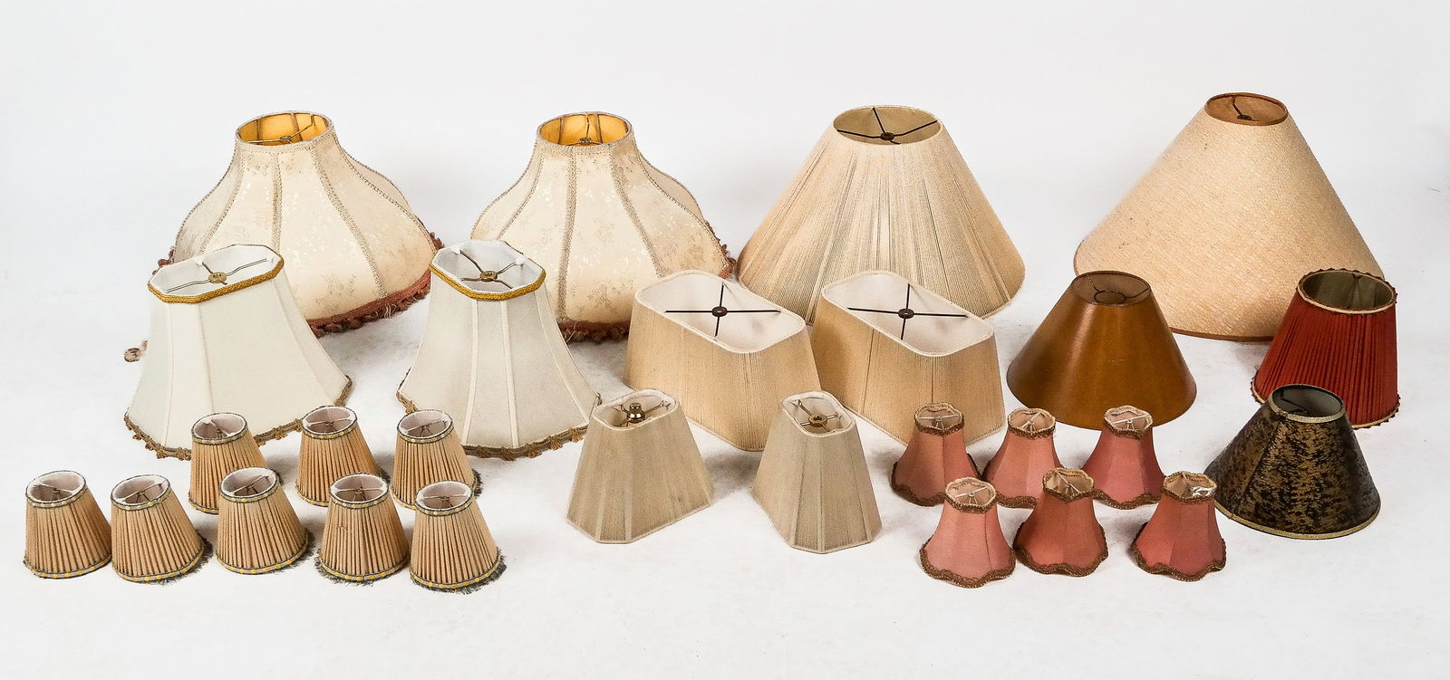 Group of Assorted Lampshades, 25+: Group of assorted lampshades and clip on chandelier and sconce lampshades, mostly in creams, pinks, and greens, including a pair of large off-white damask shaped bell-shaped lampshades with pink and g