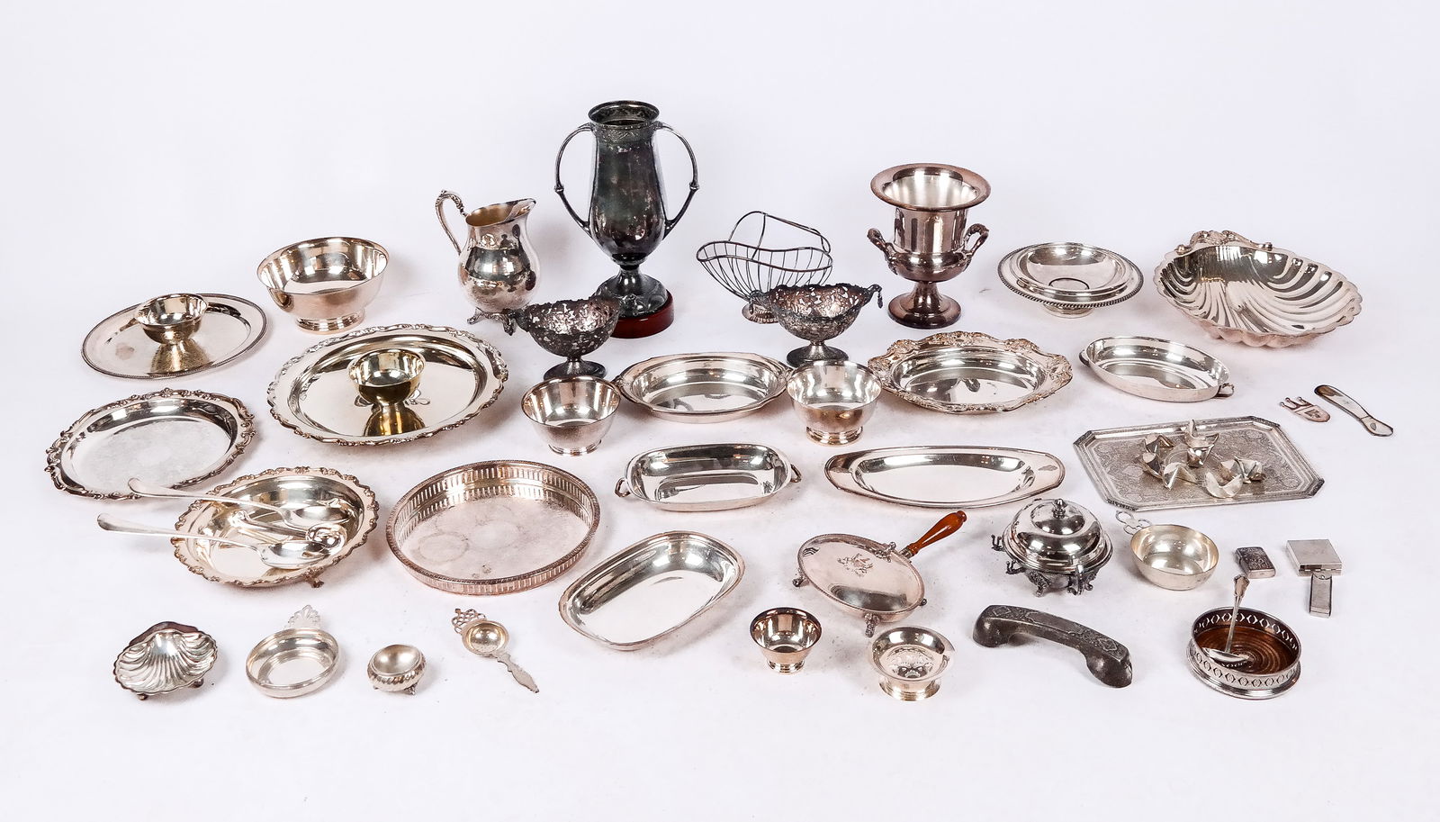 Large Group of Silver Plate: Group of silver-plated items including repousse lighter, toothpick holder, wine coaster, pill box, assorted flatware, pair of continental serving liners, serving pieces, trophy, wine bottle holder, et