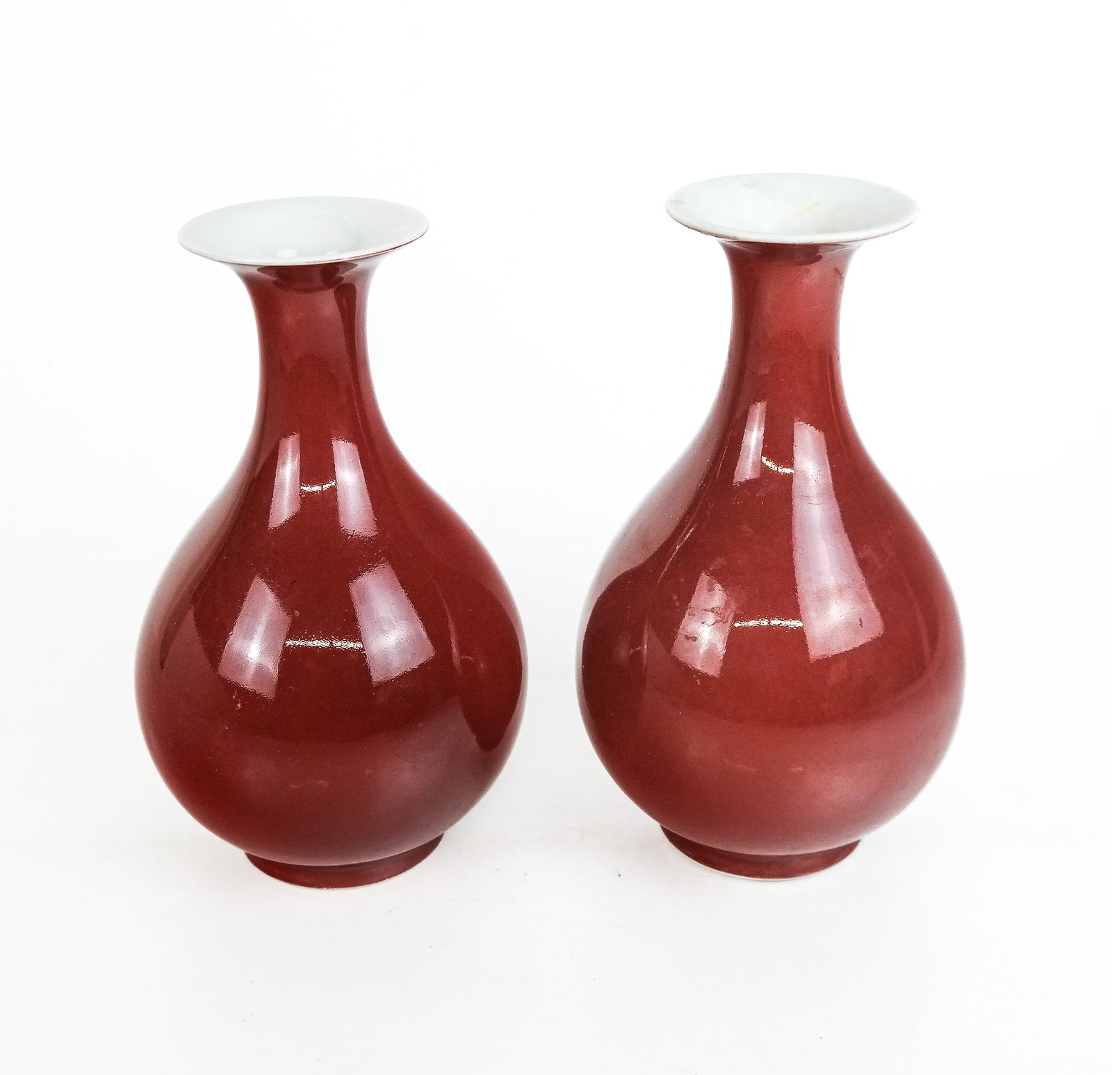 Chinese Oxblood Vases: A pair of porcelain oxblood vases, with one marked on the base. [8.5" H x 5" W x 5" D]. Overall condition is good, with one piece being slightly darker than the other.