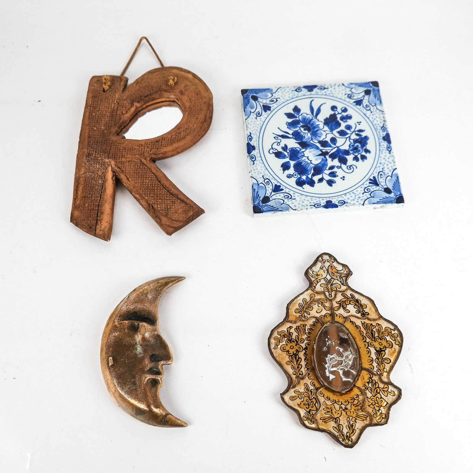 Group of Four Decorations: Group of four decorations, including a moon brass tray, a miniature Venetian-style mirror, an initial "R", and a Delft blue and white tile. [Largest: 8"H x 5.5" W]. All with wear. Condition reports an