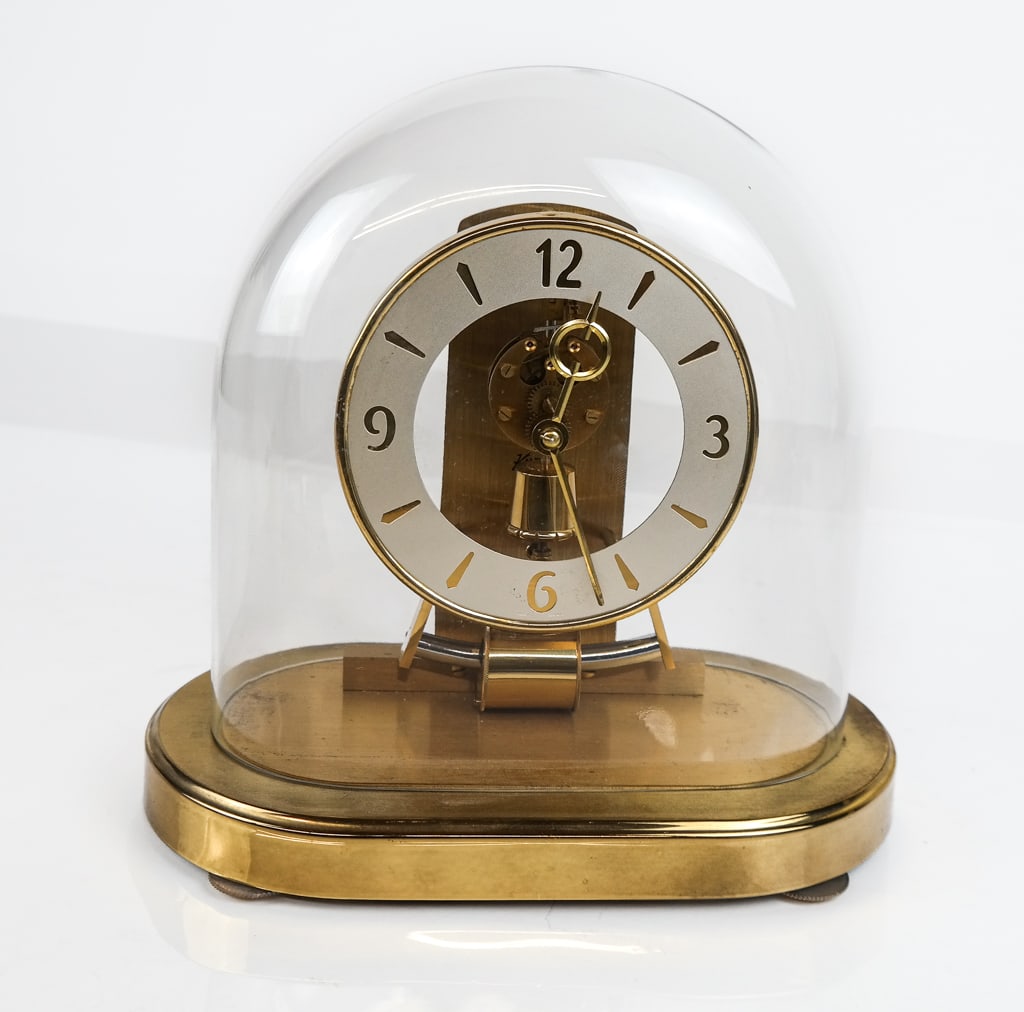Kienenger and Obergefell Metal Clock: Kienenger and Obergefell metal clock with a silvered dial, marked on verso "Kienenger and Obergefell, Made in Western Germany, 6 Jewels" [10" H x 9" W x 5" D] Overall condition is good, with wear comm