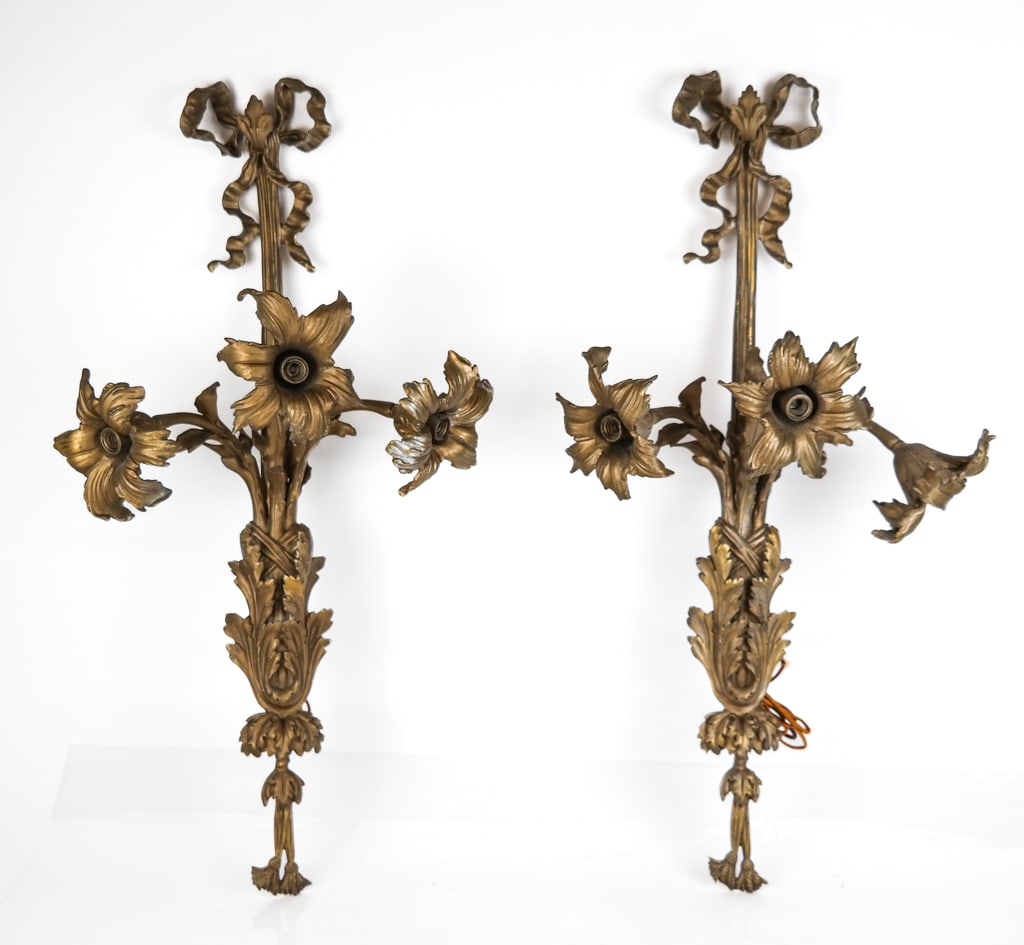 Pair Rococo Gilt Metal Three Light Sconces: Pair of gilt metal Rococo floral three light sconces, with ribbon detail at top and foliate design throughout. [29" H x 16" W x 9" D] Overall condition is good with light wear to gilding.