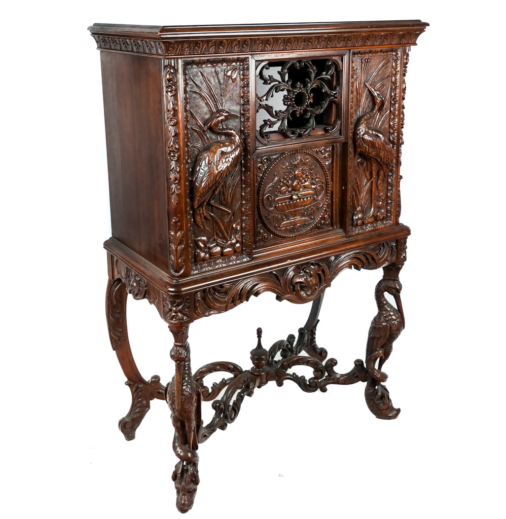 Carved Walnut Radio Cabinet: Independent Radio Company Carved Walnut Radio Cabinet with acanthus frieze above a central door flanked by two herons on over two heron and snake form legs above dolphin feet; with a screen mounted op