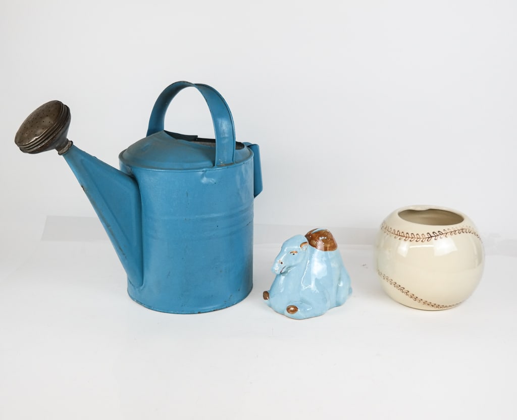 Mixed Group of Decorative Objects: A mixed group of decorative objects including a McCoy baseball form jar, a porcelain camel form piggy-bank, and a blue painted watering can. [watering can: 16" H x 10" W x 18" D]. Overall good conditi