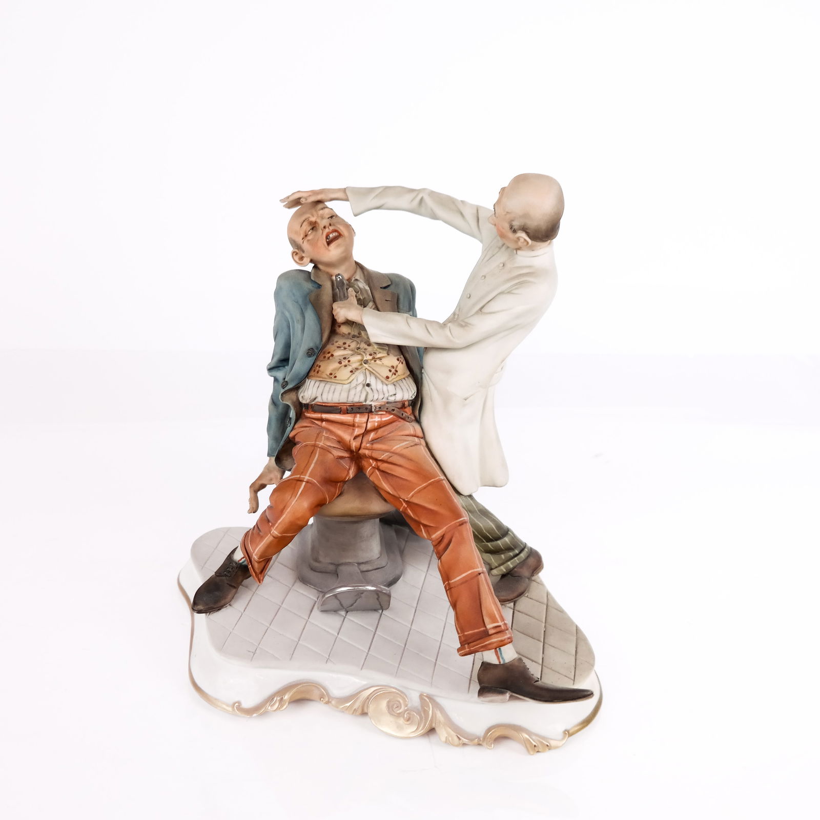 Capodimonte Porcelain Figurine of Dentist: Capodimonte porcelain figurine of a dentist extracting a tooth, mark and number to base, mark to back J.Bomallesti [9.5" H x 9" W x 8.5" W] Overall condition is good.
