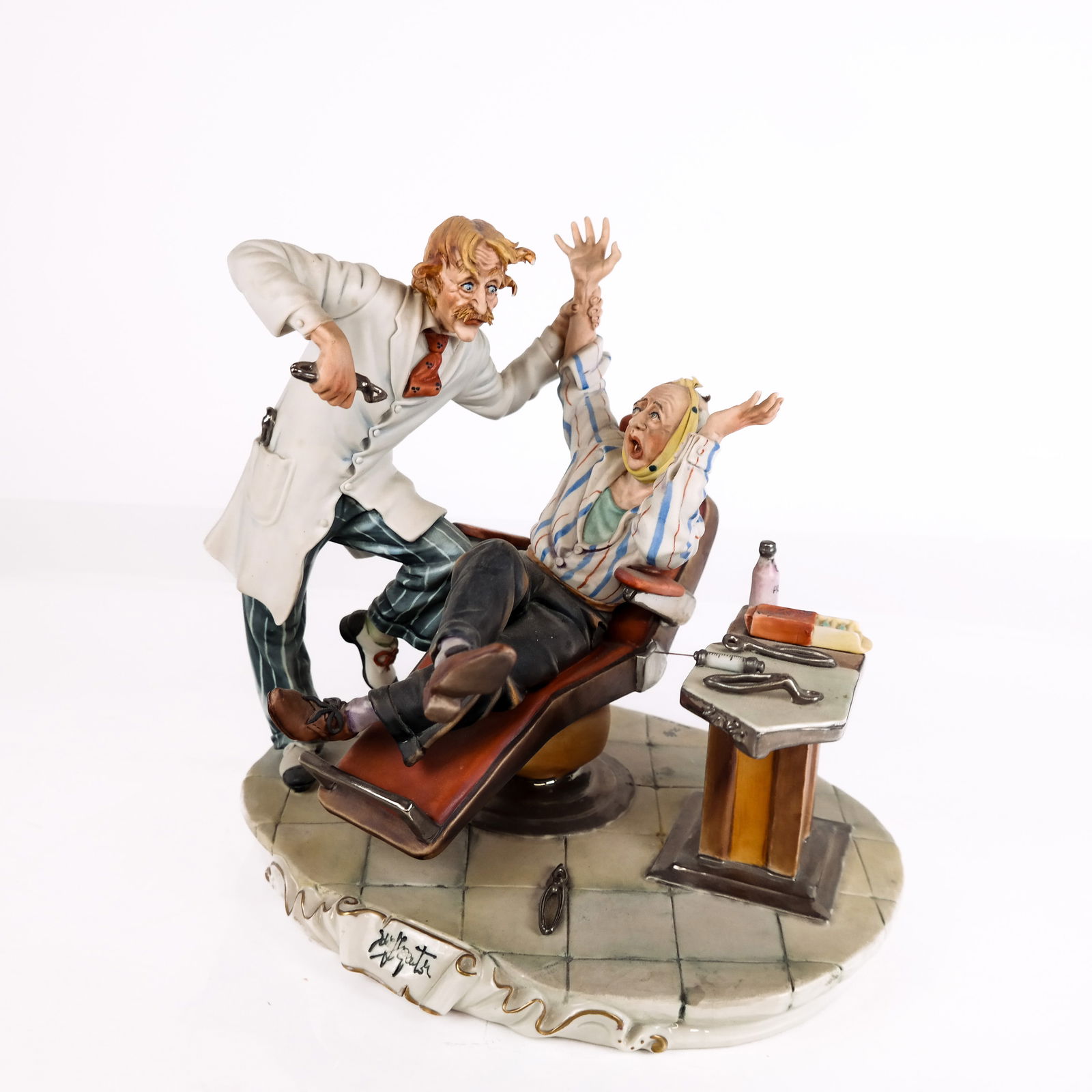 Capodimonte Porcelain Figurine of Dentist: Capodimonte porcelain figurine of a dentist extracting a tooth, mark and number to base, signed front [11" H x 10" W x 8" W] Overall condition is good.