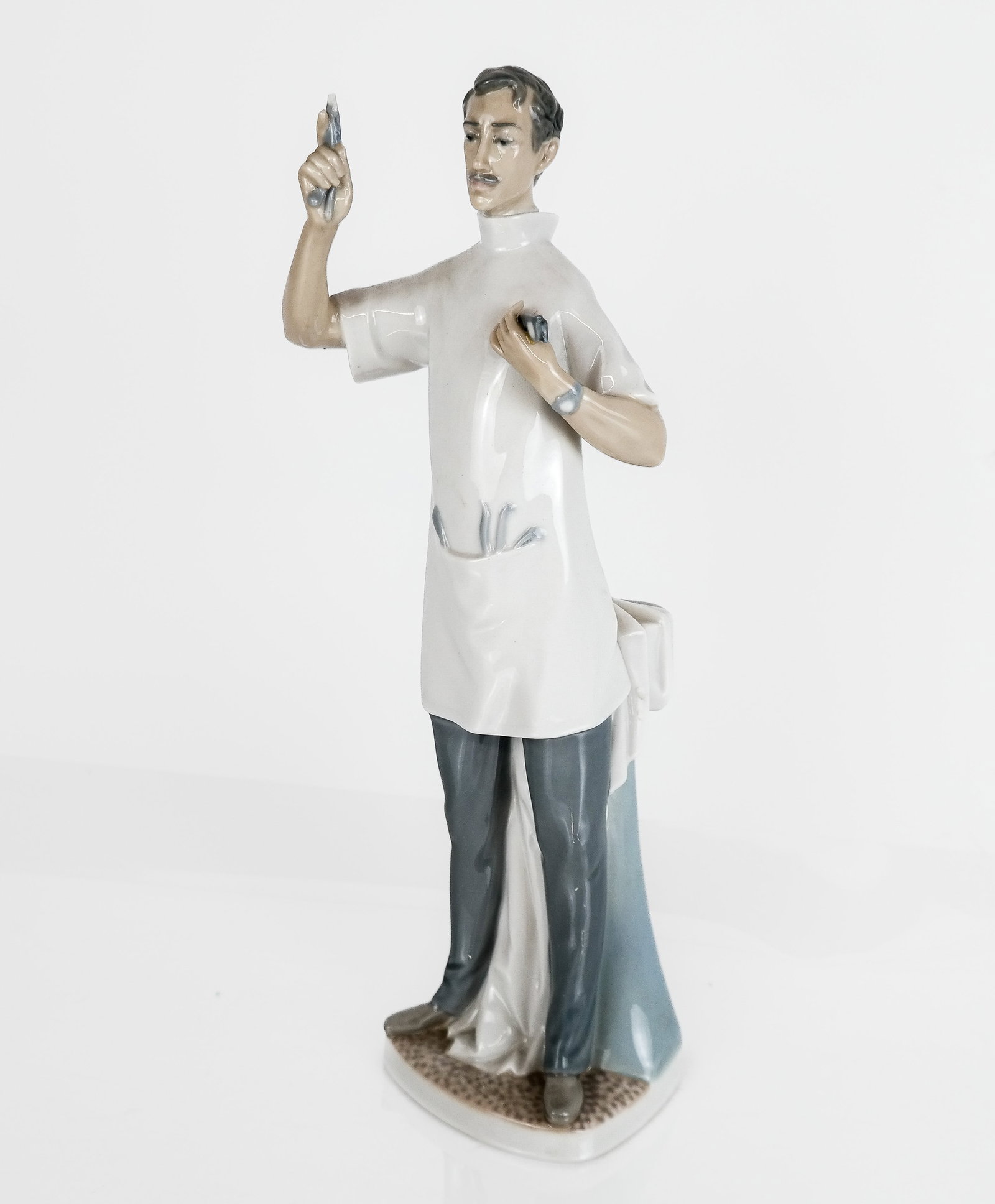 Lladro Porcelain Figure Group "Dentist": Lladro porcelain figure group "Dentist", Spanish, 20th century, mark to base [14" H x 5" W x 3" D] Overall condition is good, with hairline crack to back.