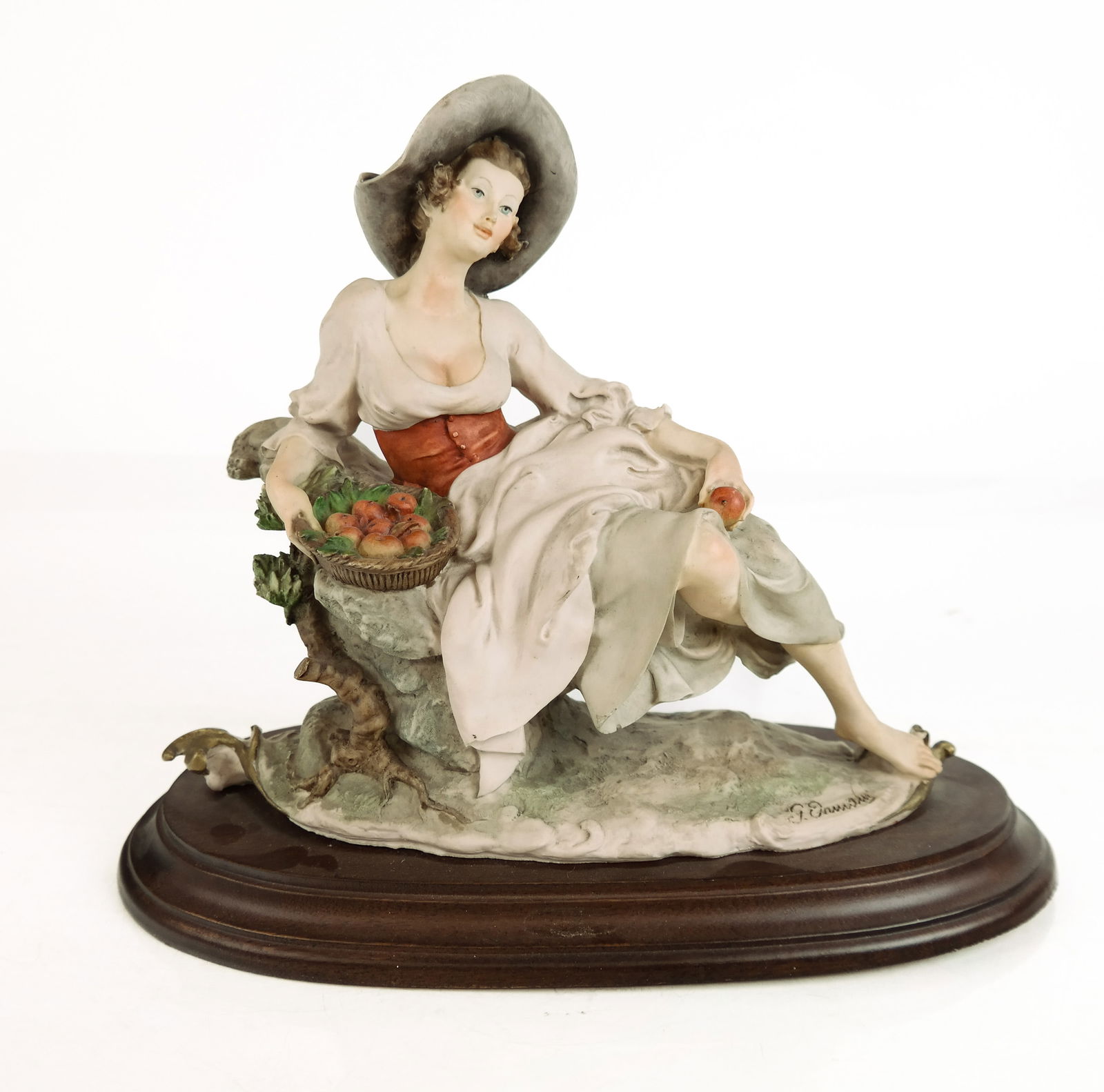 Giuseppe Armani Capodimonte Porcelain Woman: Giuseppe Armani Capodimonte hand-painted porcelain figurine of a woman holding an apple basket, 20th century, signed Giuseppe Armani to front and marked at verso and on a wooden base. [Including base: