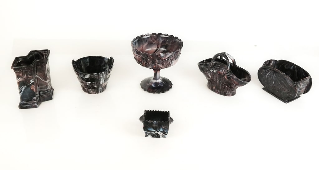 Purple Malachite / Slag Glass Tablewares, 6: Collection of dark purple malachite / slag glass tablewares comprising basket, Somersby bucket, diminutive jardiniere, jardiniere, compote, and a pillar form vessel [Compote: 5.5" H x 5.75" Diameter] 