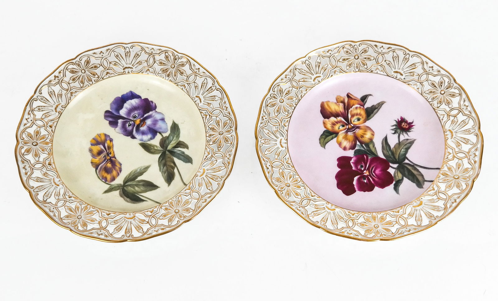 After KPM Whimsical Flower Porcelain Plates, 2: After KPM whimsical face decorated pansy plates, possibly inspired by Alice In Wonderland, probably 20th century, each with gilt decorated pierced and reticulated border framing face decorated pansies