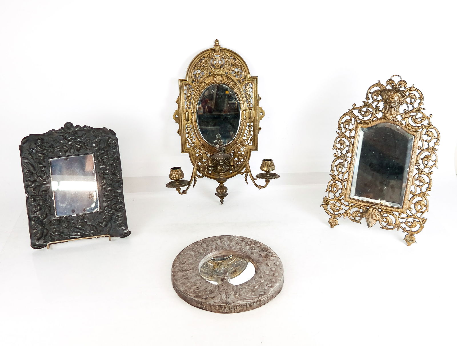 Four Vintage and Antique Mirrors: Four vintage and antique mirrors including a silver tone peacock mirror, a figural mirror with cherubs, a gilt metal mirror with beveled glass and a Bacchic mask to upper and a stand affixed to back,