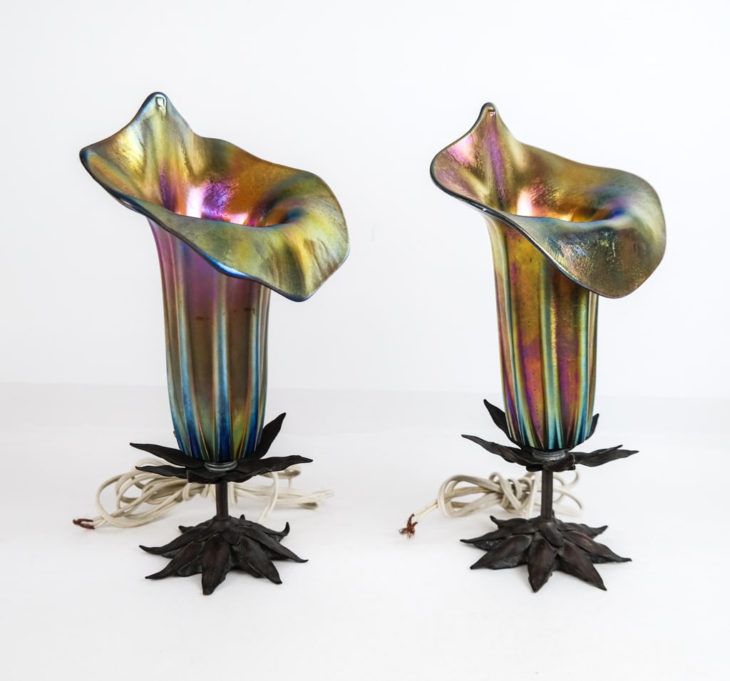 John COOK Pair of Art Glass Cala Lilly Lamps: John Cook, Phoenix Studio, pair of iridescent art glass lamps, 1989, in the form of cala lilies with metal foliate form bases, dated and signed Cook to base. [14.5" H x 7" W x 4.5" D]. Overall conditi