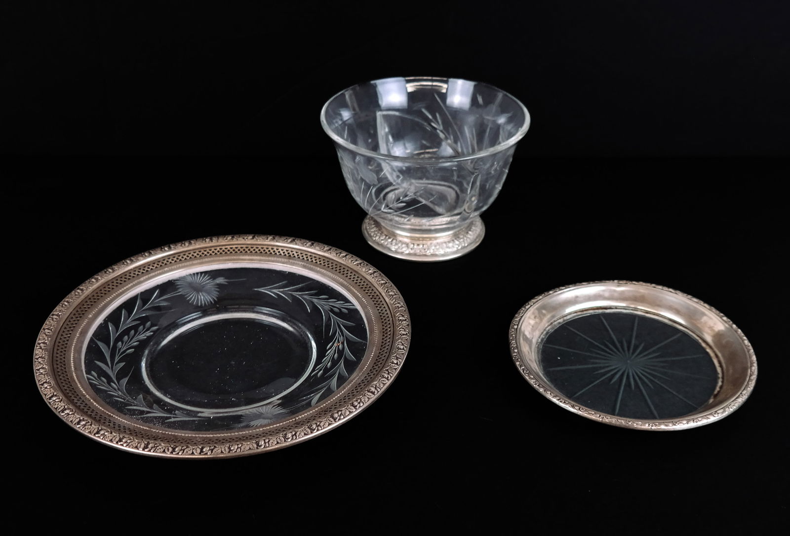 Three Sterling Silver and Glass Tablewares: Three sterling silver and cut/etched glass tablewares comprising two section condiment dish with floral repoussed foot, Frank M. Whiting Co. wine coaster with silver rim, and Wallace floral decorated