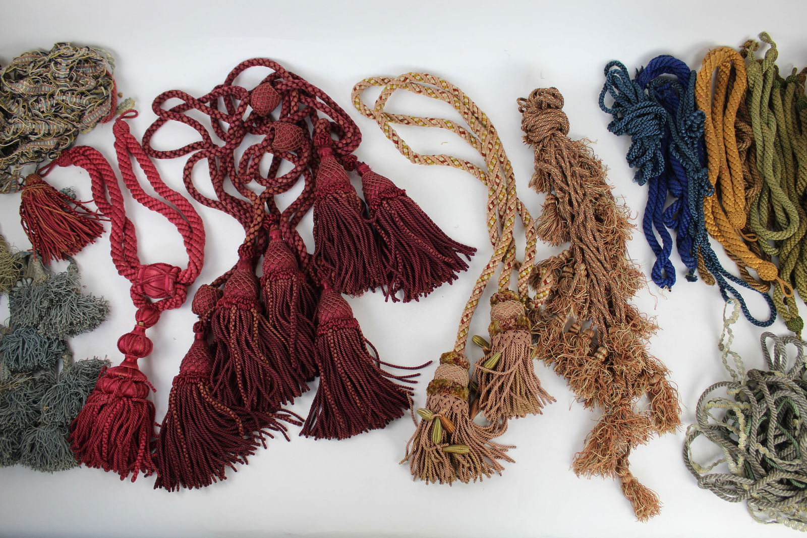 Lot of Antique Upholstery Silk Tassels & Cords: Large collection of antique silk tassels and braided cords, including a set of large wine red silk large tassels with matching cords; a pair of elaborate yellow, pink, and green silk tassels with brai