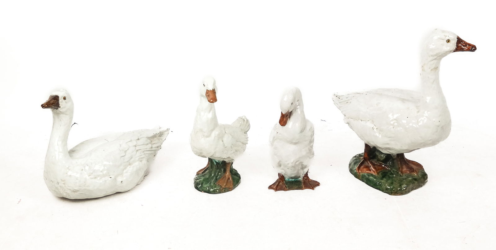 Four Glazed Terra Cotta Geese: Four glazed terra cotta geese, French, possibly Bavent, in various poses, apparently unmarked. [Largest: 23" H x 11" W x 23" D]. Overall condition is good with minor scattered wear including cracks an