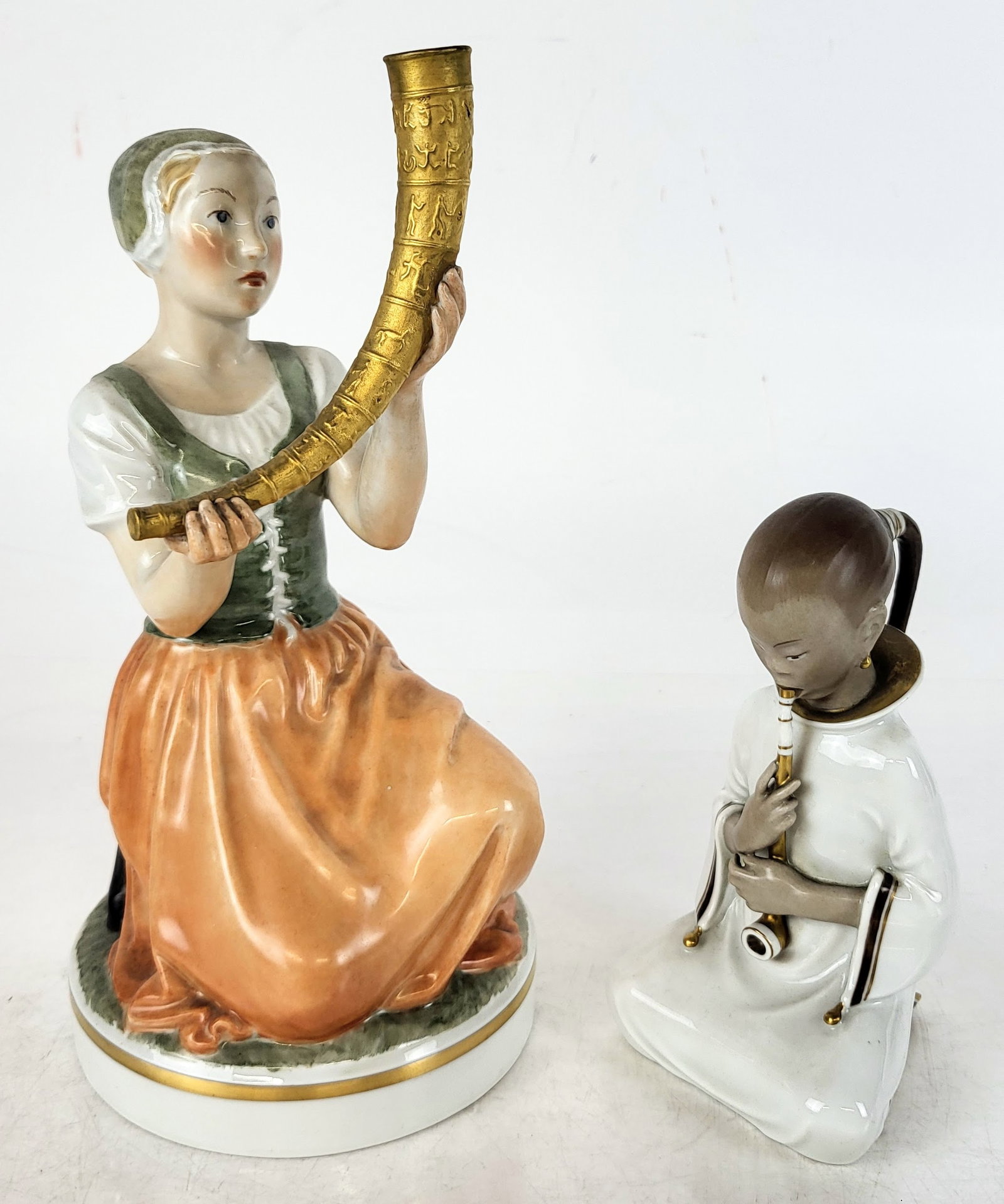 Two Royal Copenhagen Sculptures: Two Danish porcelain figures, including a woman holding a cornucopia-style vessel, and an Asian figure with a pipe. [Larger: 8" H x 4.5" Diameter (base)]. Both in good condition.